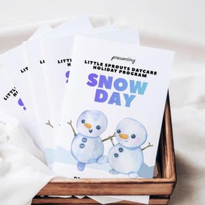 以下が含まれることがあります： 「LITTLE SPROUTS DAYCARE HOLIDAY PROGRAM SNOW DAY」の文字と雪だるまのイラストが描かれた白い紙のチラシの束。チラシは木製のトレイに入っています。