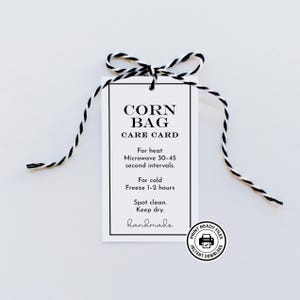 May include: A white rectangular care card with black text reading CORN BAG CARE CARD, For heat Microwave 30-45 second intervals, For cold Freeze 1-2 hours, Spot clean. Keep dry, handmade. Tied with black and white twine.