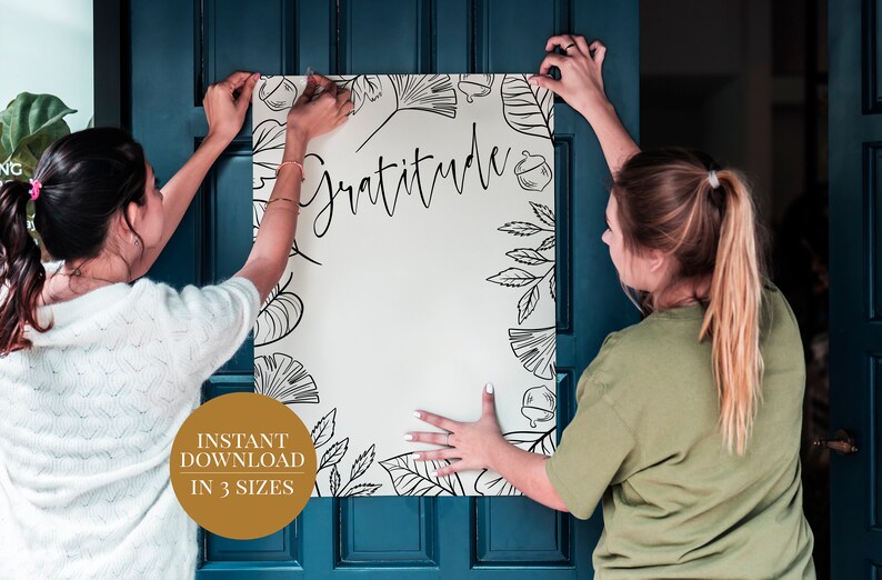 Peut inclure: Deux personnes accrochent une affiche blanche avec des motifs floraux noirs et le mot "Gratitude" sur une porte bleu sarcelle. L'affiche est disponible en t&eacute;l&eacute;chargement instantan&eacute; en trois tailles.