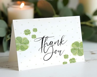 May include: A white thank you card with green four-leaf clover illustrations and white polka dots. The card says "Thank You" in black cursive.