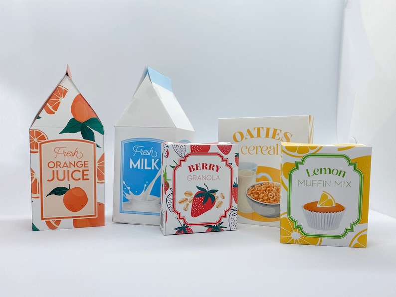 May include: Five colorful cardboard boxes with different food items. The boxes are labeled "Fresh Orange Juice", "Fresh Milk", "Berry Granola", "Oaties Cereal", and "Lemon Muffin Mix".