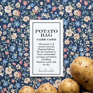 May include: A white card with the text "POTATO BAG CARE CARD" and care instructions, including microwave and washing instructions. The card is on a blue floral fabric background, with several potatoes in the foreground.