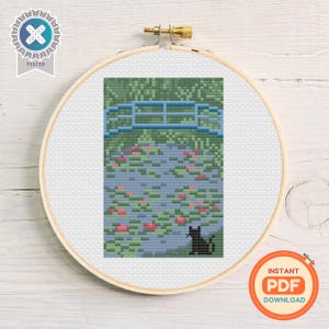 May include: Cross-stitch embroidery in a wooden hoop. The design features a blue bridge over a pond with pink water lilies and a black cat. The background is green. The words "INSTANT PDF DOWNLOAD" are in a circle.