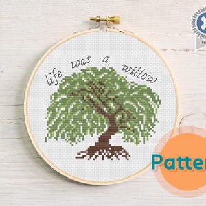 May include: Cross stitch pattern featuring a willow tree with the text "life was a willow". The pattern is displayed in a wooden embroidery hoop.