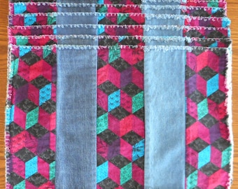 May include: Set of six denim placemats with a geometric pattern in shades of pink, blue, green, and black. The placemats have a frayed edge.