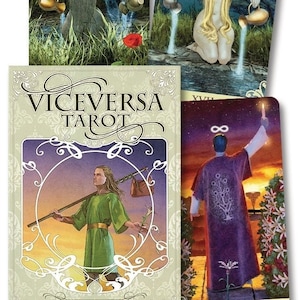 May include: A tarot deck box with the title "Viceversa Tarot" in a decorative font. The box is beige with a gold border and features an illustration of a person holding a staff and a bag. The box is open to reveal a card with a purple-robed person standing on a path with a tree behind them.