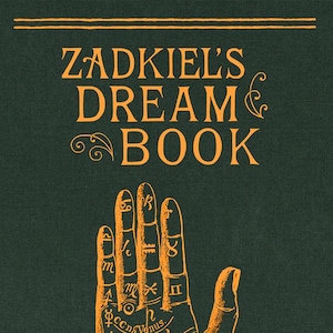 May include: A dark green book cover with the title "Zadkiel's Dream Book" in orange lettering. An illustration of a palm with astrological symbols and lines is featured. The book has a textured appearance.