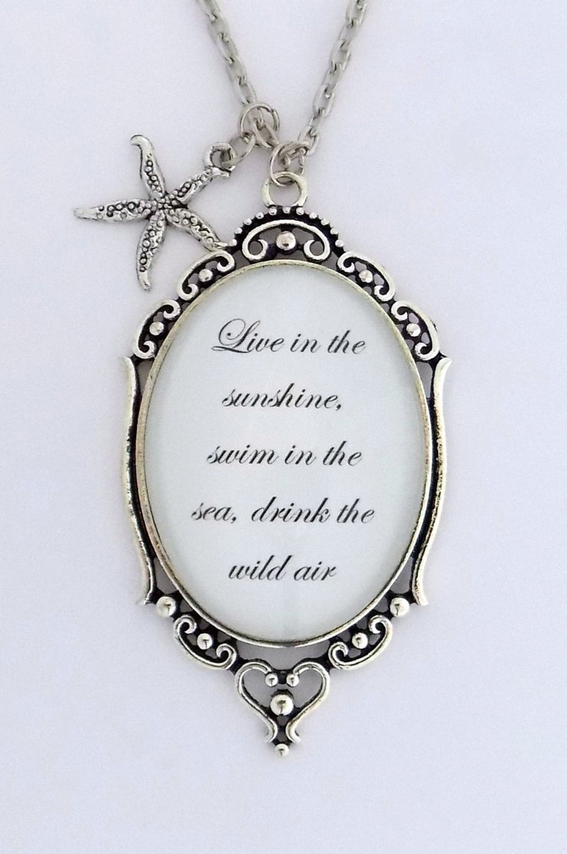 May include: Silver necklace with a silver oval pendant featuring the quote "Live in the sunshine, swim in the sea, drink the wild air". The pendant is attached to a silver chain with a silver starfish charm.