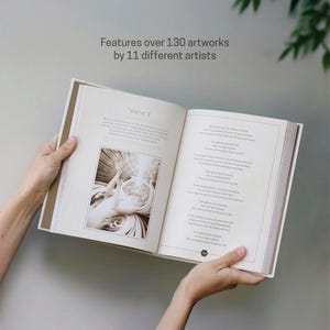 May include: An open book with a detailed illustration and text on the pages. The book is held open, revealing a black and white image and text. The text at the top reads "Features over 130 artworks by 11 different artists."