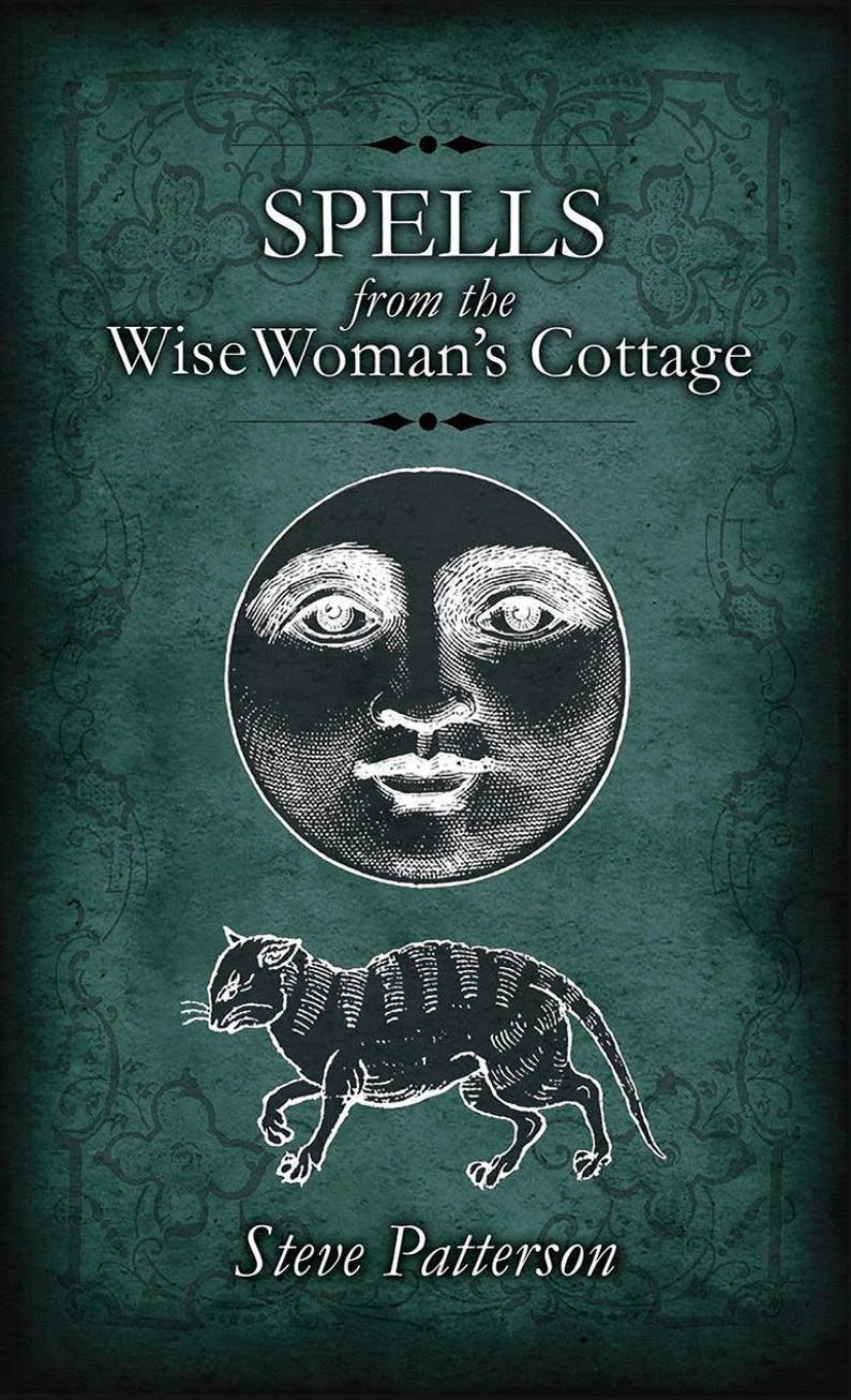 May include: A book cover with a green background and white text that reads "Spells from the Wise Woman's Cottage" with a black and white illustration of a moon face and a cat.