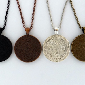 May include: Four round pendant necklaces with different coloured chains. The pendants are black, copper, silver, and bronze.