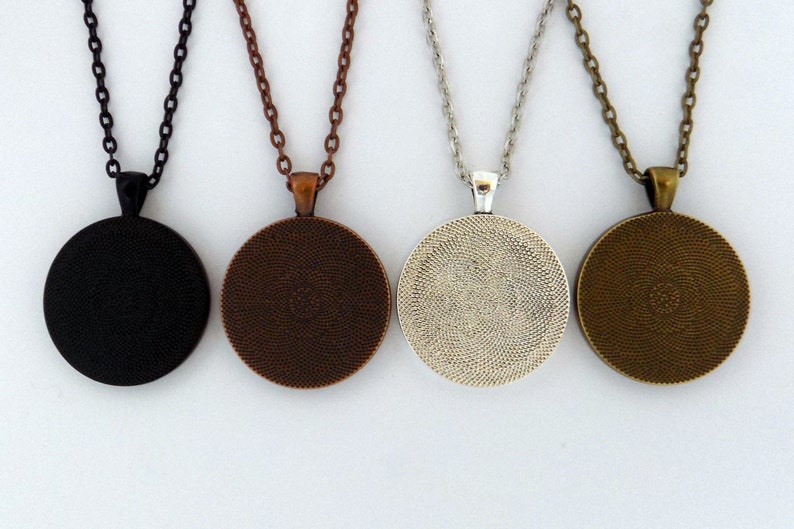 May include: Four round pendant necklaces with different coloured chains. The pendants are black, copper, silver, and bronze.