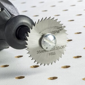 May include: A close-up of a silver rotary tool blade with the text "35mm Max 6.35x35T HSS 20,000 RPM" printed on it. The blade is attached to a black rotary tool.