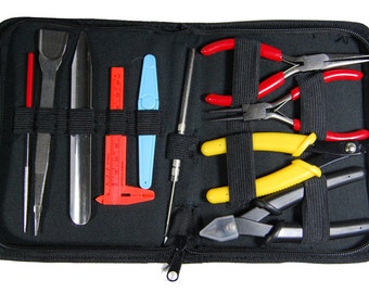 May include: A black zippered case containing a set of jewelry making tools. The tools include tweezers, a metal scraper, a ruler, a wire cutter, a needle, and four pairs of pliers with red, yellow, and black handles.