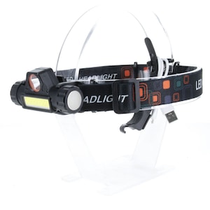 May include: A black headlamp with a white LED light and a black and orange patterned headband. The headlamp has a USB charging port and the text "LED HEADLIGHT" is printed on the headband.