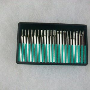 Op de afbeelding: Een set van 20 diamantbezet rotatiegereedschap in een zwarte kunststof koffer met een teal blauwe rand. De bits zijn gerangschikt in rijen en zijn allemaal even lang.