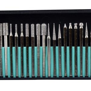 Puede incluir: Un juego de fresas rotativas en una caja de plástico negro con un inserto de color turquesa. Las brocas plateadas tienen varias formas, incluyendo cilíndrica, cónica y esférica. El juego está diseñado para herramientas rotativas.