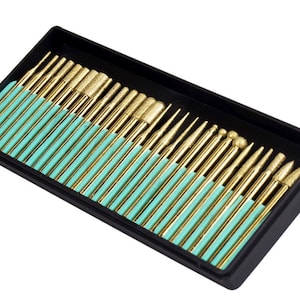 May include: A set of 30 gold-colored diamond burrs in a black plastic case with a teal-colored foam insert. The burrs are arranged in rows and are of various shapes and sizes.