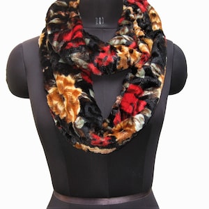 May include: A black, red, and gold floral print infinity scarf made of soft, plush fabric.