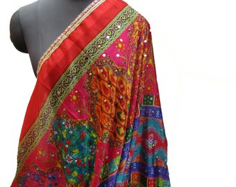 May include: A colourful patterned shawl with a red border and gold trim. The shawl is decorated with small mirrors and intricate embroidery.