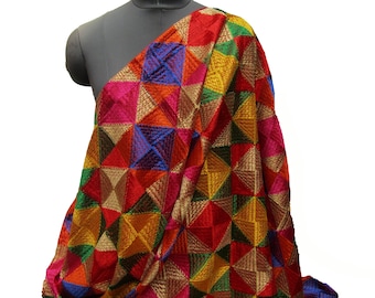 Può includere: Un tessuto colorato con un motivo geometrico di quadrati e triangoli in tonalità di rosso, rosa, blu, verde, giallo e oro. Il tessuto è ricamato con un design in rilievo.