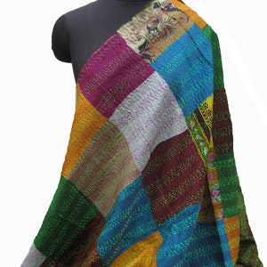 May include: A colorful patchwork quilt made from different fabrics in shades of green, blue, yellow, pink, brown, and white. The quilt is stitched together with a running stitch and has a unique, handmade look.
