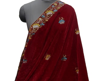 May include: A red velvet shawl with floral embroidery in shades of gold, blue, and white. The shawl is draped over a mannequin.