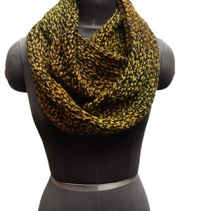 May include: A black and yellow infinity scarf made of knitted yarn. The scarf is displayed on a black mannequin.