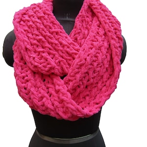 May include: A bright pink knitted infinity scarf made of a soft, fuzzy yarn. The scarf is folded in half and draped over a mannequin's neck.