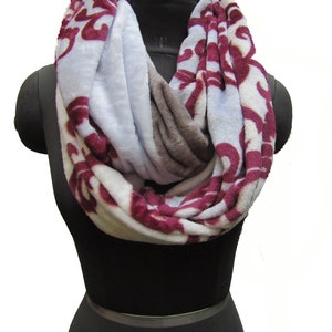 May include: A soft, cozy infinity scarf with a white base and a burgundy floral pattern. The scarf is made of a plush fabric and is perfect for keeping warm in the winter.