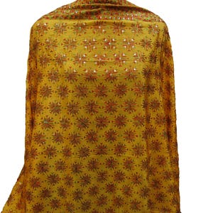 May include: A mustard yellow shawl with a repeating pattern of red, green, and gold embroidered stars. The shawl is made of a soft, lightweight fabric and has a delicate, flowing drape.