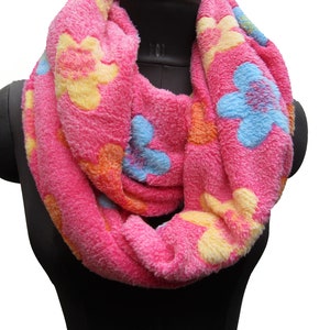 May include: A pink infinity scarf with a floral pattern in yellow, orange, and blue.