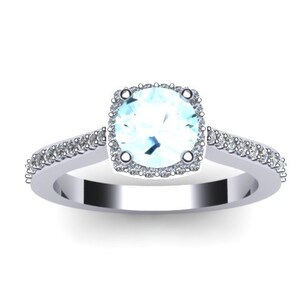 May include: A silver ring with a light blue gemstone surrounded by a halo of smaller diamonds. The band is also set with smaller diamonds.