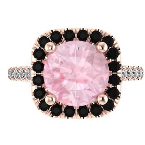 May include: A rose gold ring with a large pink gemstone surrounded by a halo of black diamonds. The band is set with smaller white diamonds.
