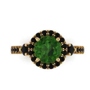 May include: A gold ring with a large green gemstone surrounded by a halo of black gemstones.