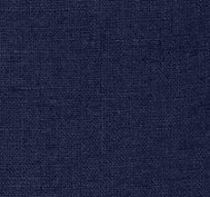 Op de afbeelding: Een close-up van een marineblauwe stof met een subtiel rasterpatroon. De textuur suggereert linnen of een vergelijkbaar geweven materiaal, met een licht ruwe, natuurlijke uitstraling. De kleur is een diep, effen marineblauw, wat een klassieke en veelzijdige uitstraling geeft.