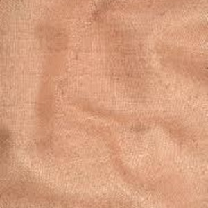 Op de afbeelding: Close-up van een perzik-kleurige stof met een getextureerd oppervlak en zachte plooien. Het materiaal heeft een subtiele glans, wat suggereert dat het een lichte stof is, zoals linnen of een vergelijkbare weefsel, met een delicate, bijna transparante kwaliteit.