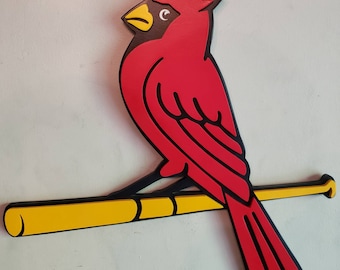 May include: A red cardinal bird with black outlines and yellow beak perched on a yellow baseball bat with black outlines.