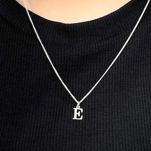 May include: A silver chain necklace with a silver letter E pendant.