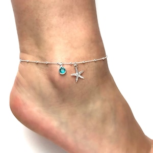 May include: Silver anklet with a turquoise blue gemstone and a silver starfish charm.