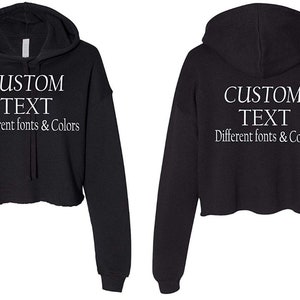 May include: Black cropped hoodie with a drawstring hood. The hoodie has white text that says "CUSTOM TEXT Different fonts & Colors".