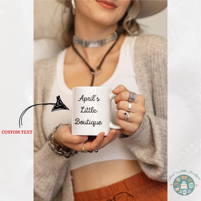 Peut inclure: Une tasse en c&eacute;ramique blanche avec du texte noir qui dit "April's Little Boutique".