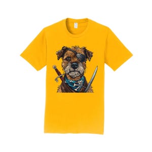 Peut inclure: Un t-shirt jaune avec une image de dessin animé d'un terrier brun et noir portant un cache-œil et un bandana bleu avec un motif de crâne et d'os croisés. Le chien tient deux épées dans ses pattes.