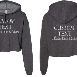 May include: A gray cropped hoodie with a white drawstring and white text that reads "CUSTOM TEXT Different fonts & Colors".