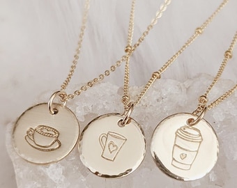 May include: Three gold necklaces with different coffee-themed pendants. The pendants are round and feature a coffee cup, a mug, and a to-go coffee cup.