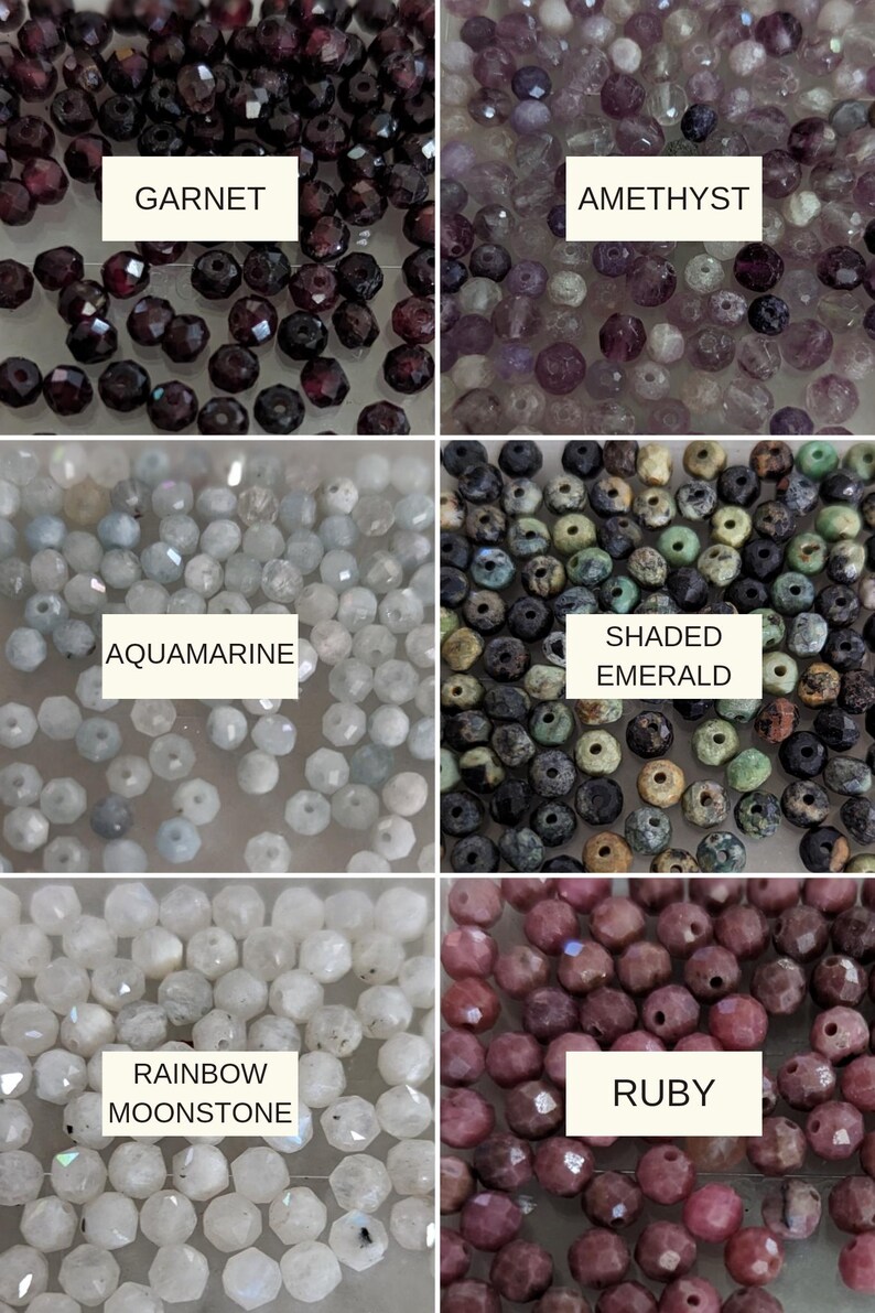 May include: A collection of faceted gemstone beads organized in six labeled sections: dark red Garnet, light purple Amethyst, pale blue Aquamarine, multi-colored Shaded Emerald, translucent white Rainbow Moonstone, and deep pink Ruby beads.