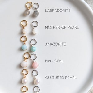 May include: Six different gemstone charms on gold and silver jump rings. The charms are Labradorite, Mother of Pearl, Amazonite, Pink Opal, Cultured Pearl, and Green Turquoise.