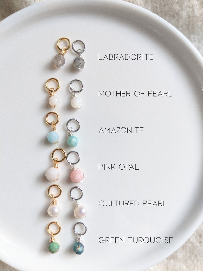 May include: Six different gemstone charms on gold and silver jump rings. The charms are Labradorite, Mother of Pearl, Amazonite, Pink Opal, Cultured Pearl, and Green Turquoise.