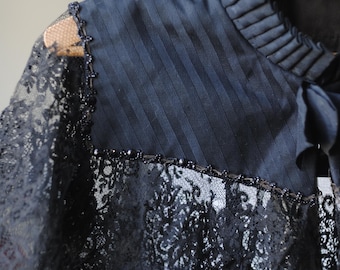 May include: A black lace collar with a ruffled neckline and beaded trim. The collar is made of delicate lace and has a vintage look.