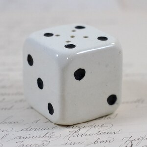 May include: White ceramic dice salt and pepper shaker with black dots. The dice has six sides and is a kitchen decor item.